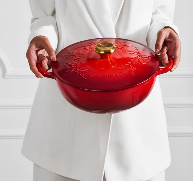woman holding a red holly patterned Dutch Oven