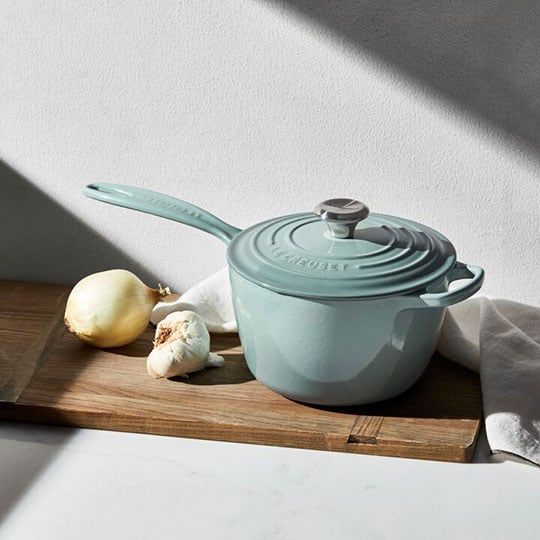 sea salt blue green cast iron saucepan on counter with onion and garlic
