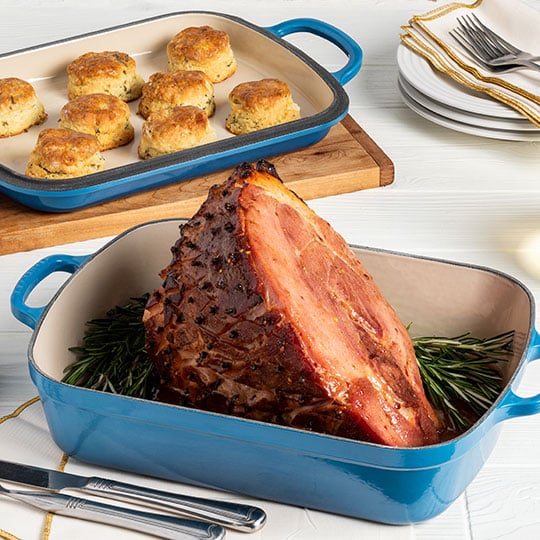 ham in a roaster alongside biscuits on a cast iron sheet pan lid
