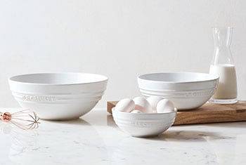 three white bowls of varying sizes pictured with eggs