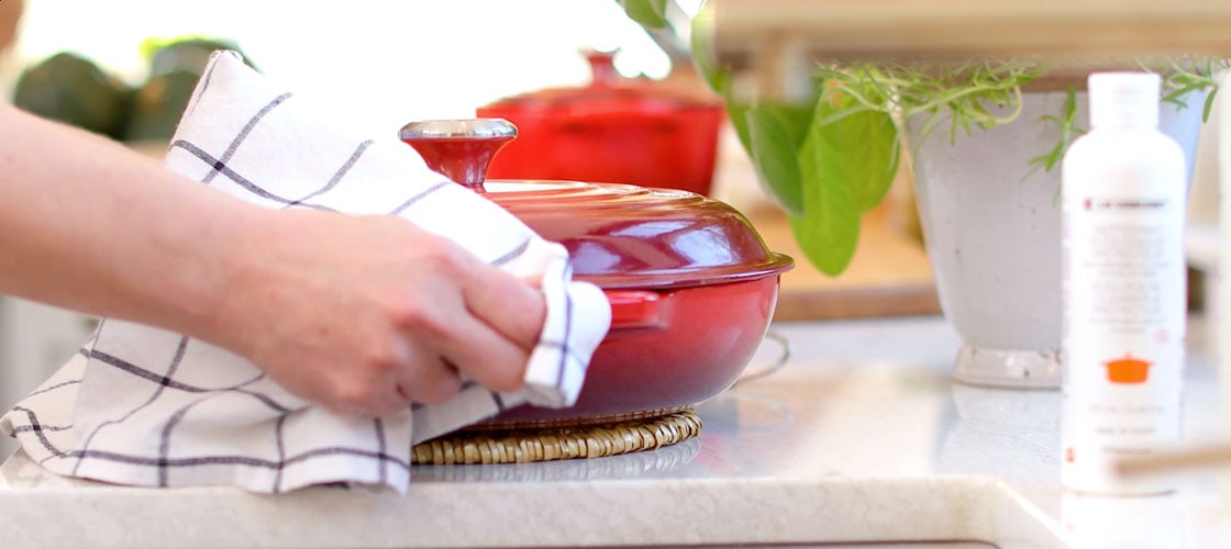 hands placing a cast iron braiser on a counter